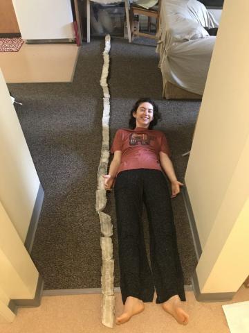 Elizabeth Patterson, UCI Ph.D. candidate in Earth system science, laying next to a 12-foot-long segment of a stalagmite found in a cave in Vietnam.
