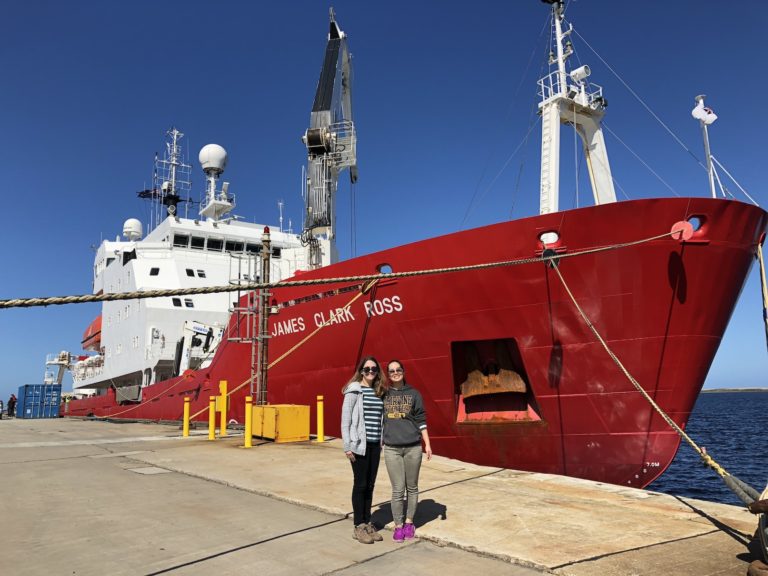 Researchers standing in front of a red research ship