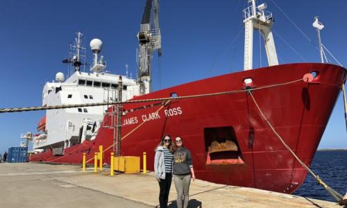 Researchers standing in front of a red research ship